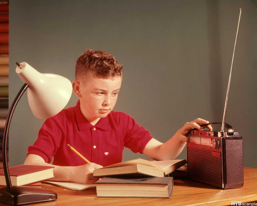 En gutt hører på radio mens han gjør leksene